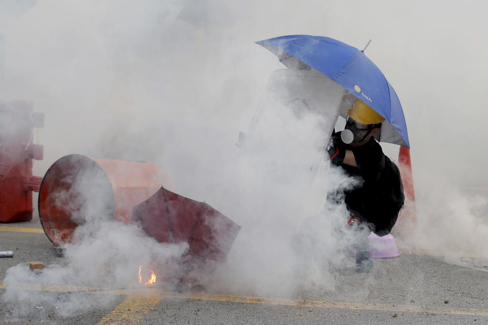 A protester is shrouded by tear gas in Hong Kong, Monday, Aug. 5, 2019. Droves of protesters filled public parks and squares in several Hong Kong districts on Monday in a general strike staged on a weekday to draw more attention to their demands that the semi-autonomous Chinese city's leader resign.(AP Photo/Kin Cheung)