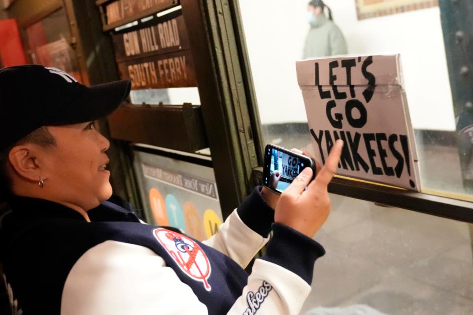 Julie Guerrero, of Brooklyn, displays a sign as she rides a vintage subway car on her way to her first Opening Day, at Yankee Stadium. Thursday, March 30, 2023