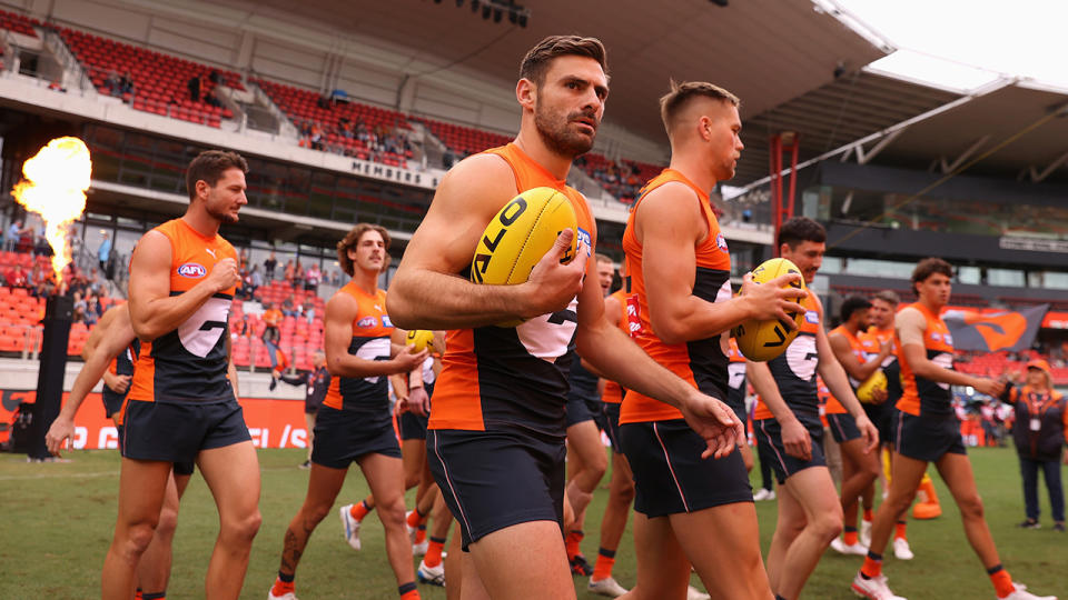 Stephen Coniglio walks onto the ground flanked by GWS Giants teammates.