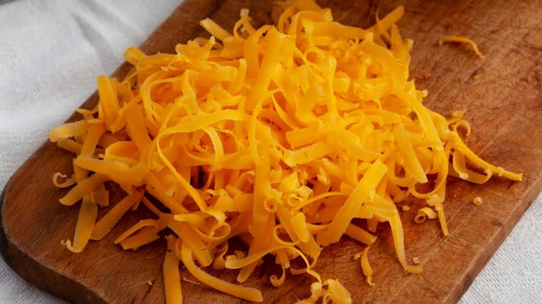 Freshly grated cheddar cheese on a board