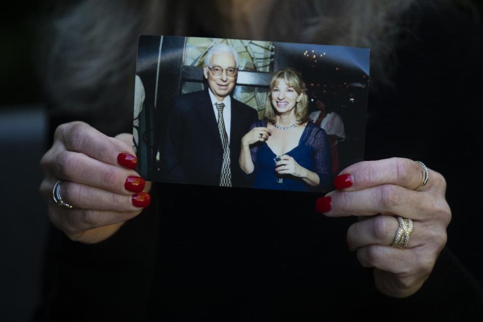 A close-up of a woman's hands holding a photo of her brother and sister