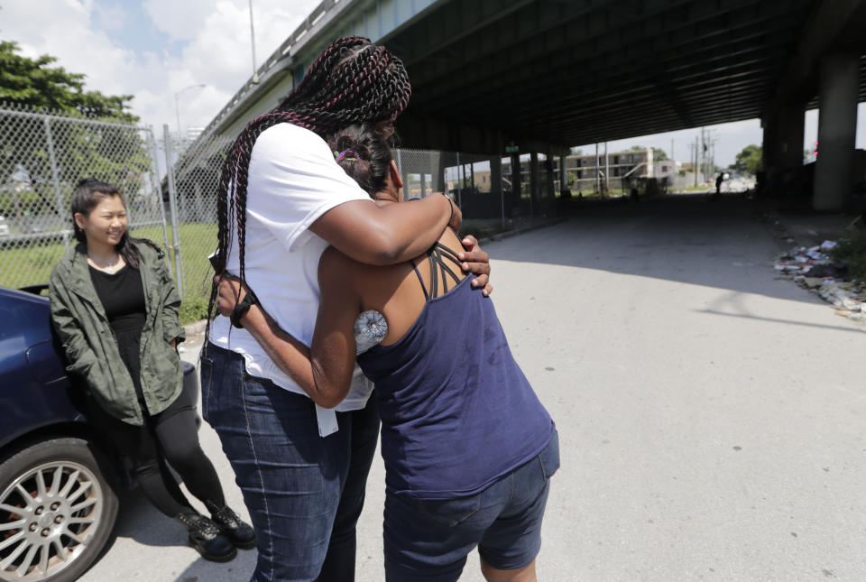 In this Wednesday, July 24, 2019, photo Ivette Naida, right, is hugged by Chevel Collington, left, of the IDEA Exchange, in Miami. Naida is participating in the University of Miami-sponsored program, which provides HIV-infected homeless people with secure medication lockers or delivers small quantities of medicine to them directly. Naida, who was diagnosed with HIV more than a decade ago, lives underneath a Miami highway overpass and has no safe place to keep her belongings. (AP Photo/Lynne Sladky)