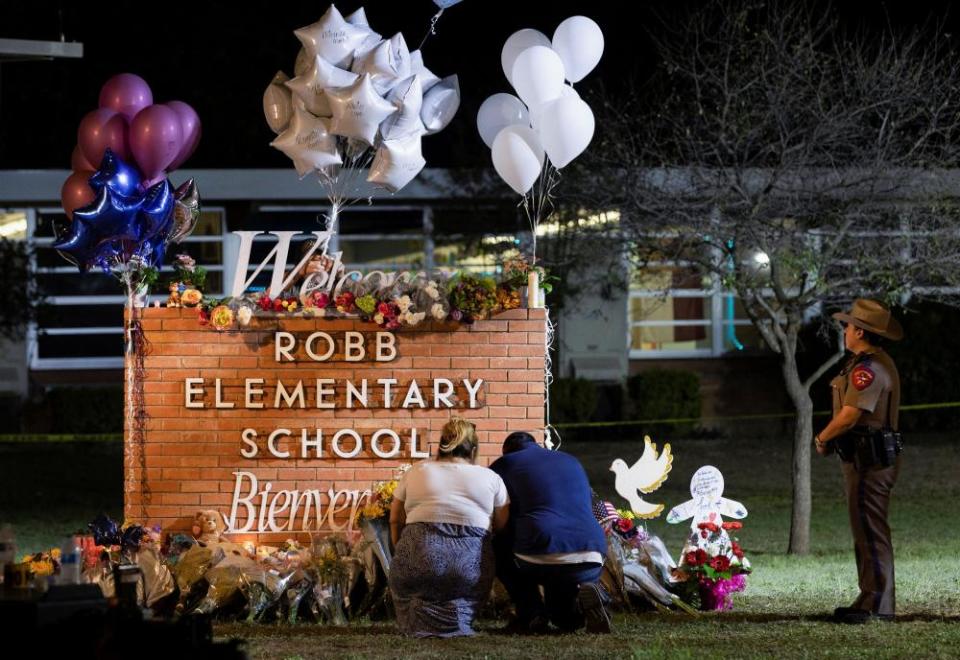 Stephanie and Michael Chavez of San Antonio pay their respects at a makeshift memorial outside Robb Elementary School.