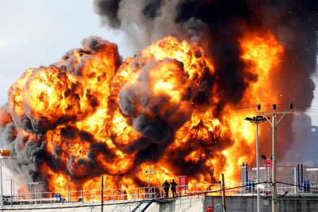 People stand opposite a blaze that erupted in a fuel tank at Oil Refineries Ltd in the Israeli northern city of Haifa December 25, 2016. REUTERS/Baz Ratner