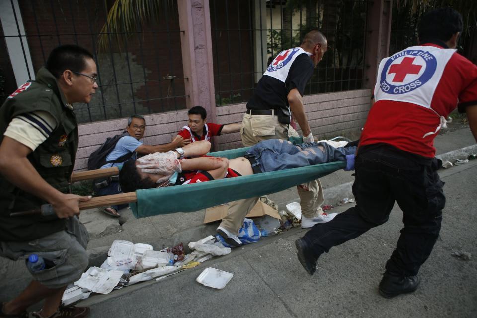 Philippine Red Cross personnel carry a wounded colleague on a stretcher after a mortar attack by Muslim rebels near the scene of fighting between government soldiers and Muslim rebels from the Moro National Liberation Front (MNLF) in Zamboanga city in southern Philippines September 13, 2013. (REUTERS/Erik De Castro)