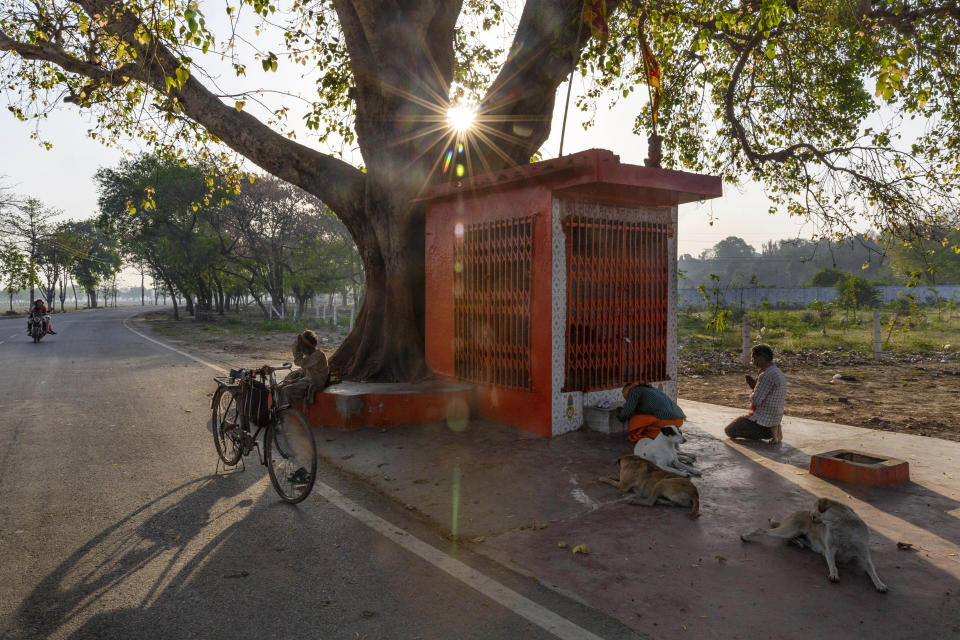 Impoverished Indians offer prayers outside a roadside Hindu temple closed on account of lockdown to prevent the spread of new coronavirus in Prayagraj, India, Wednesday, April 1, 2020. India's 21-day lockdown has effectively kept 1.3 billion people at home for all but essential trips to places like markets or pharmacies. But the world's largest lockdown has turned into a humanitarian crisis for India's impoverished people. The new coronavirus causes mild or moderate symptoms for most people, but for some, especially older adults and people with existing health problems, it can cause more severe illness or death. (AP Photo/Rajesh Kumar Singh)