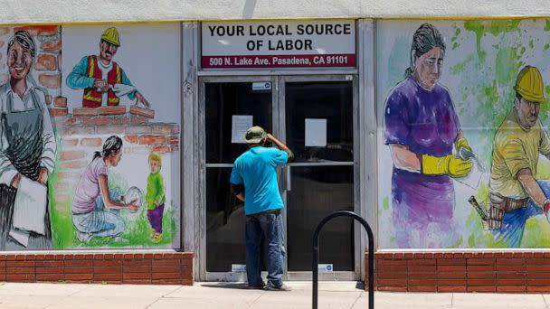 PHOTO: A person looks inside the closed doors of the Pasadena Community Job Center in Pasadena, Calif., May 7,2020. (Damian Dovarganes/AP, FILE)