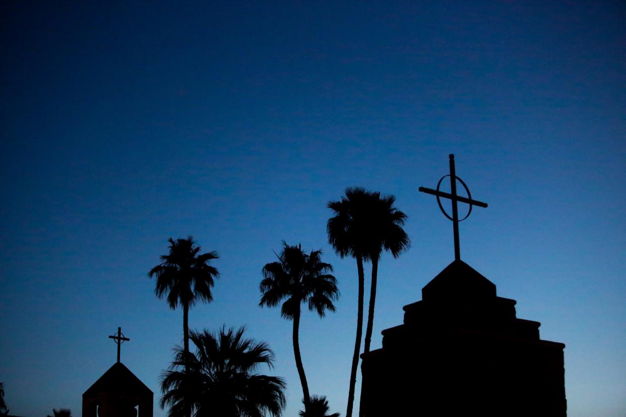 The sun begins to rise behind a California church. Singing or chanting isn't permitted in houses of worship in the Golden State to help the coronavirus from spreading, but that isn't stopping everyone.
