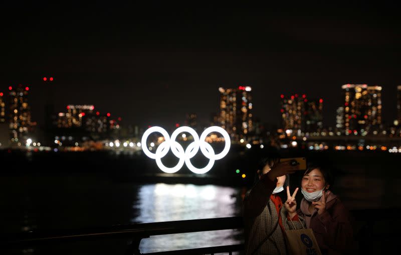 People take selfies in front of the giant Olympic rings at the waterfront area at Odaiba Marine Park in Tokyo