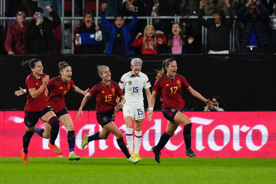 Spanish players celebrate scoring a goal against the USWNT as Rapinoe screams in frustration.
