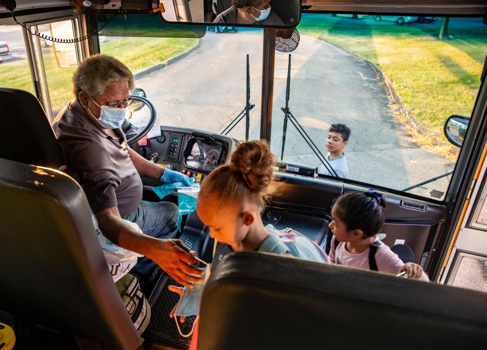 Des Moines, Iowa, school bus driver Jim Booker hands out masks as he picks up kids Sept. 14. Masks are required on school buses around the country, but that's a difficult rule to enforce.