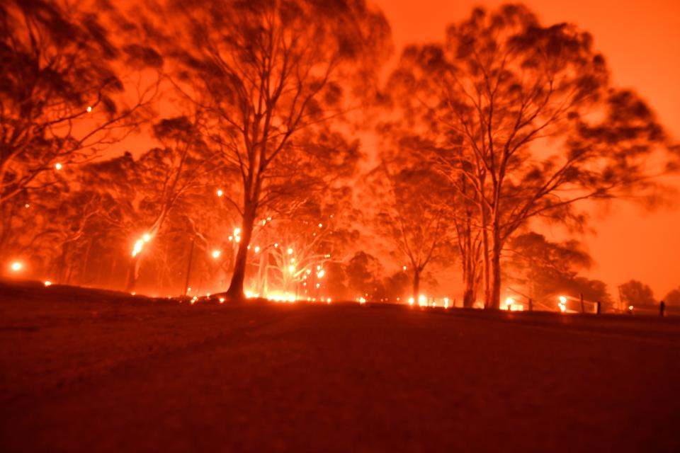 The afternoon sky glows orange from bushfires in the area around the town of Nowra in the Australian state of New South Wales on December 31. (Photo by SAEED KHAN/AFP via Getty Images)