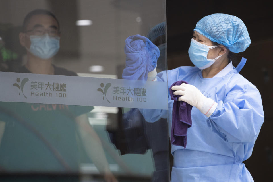 A worker cleans the glass door to a health center for COVID-19 testing in Beijing on Wednesday, June 17, 2020. The Chinese capital on Wednesday canceled more than 60% of commercial flights and raised the alert level amid a new coronavirus outbreak, state-run media reported. (AP Photo/Ng Han Guan)