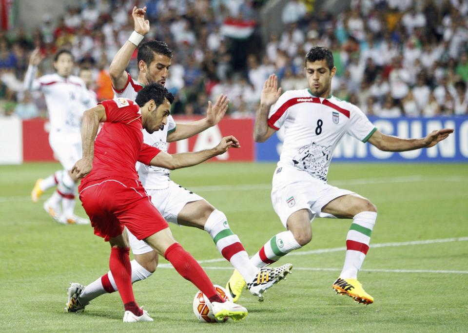 Bahrain's Sayed Ahmed Jaafar is challenged by Iran's Morteza Pouraliganji and Iran's Ehsan Hajisafi during their Asian Cup Group C soccer match at the Rectangular stadium in Melbourne