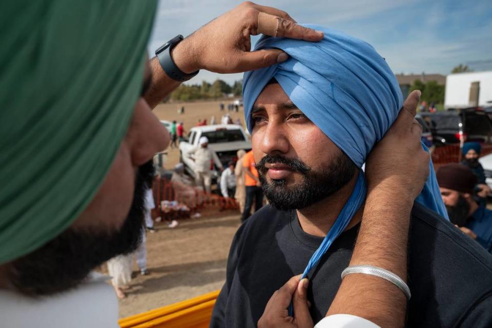 Jagdeep Mann, left, of Seattle, ties a turban on Gurpreet Singh, of New York, at the Yuba City Nagar Kirtan parade on Sunday, Nov. 5, 2023. The event draws Sikhs from all over the United States.
