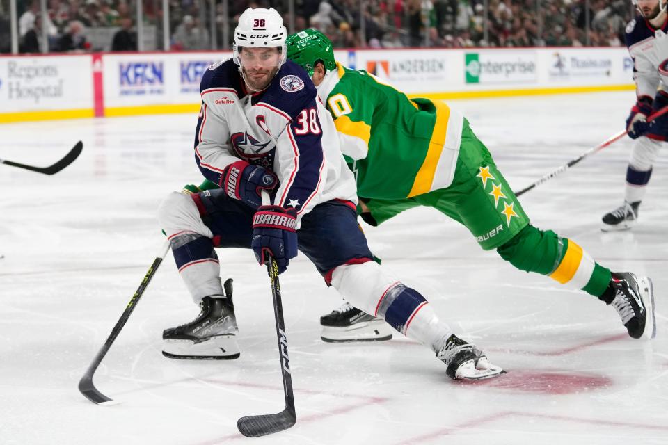 Columbus Blue Jackets center Boone Jenner (38) skates with the puck as Minnesota Wild left wing Marcus Johansson, back, defends during the third period of an NHL hockey game Saturday, Oct. 21, 2023, in St. Paul, Minn. (AP Photo/Abbie Parr)