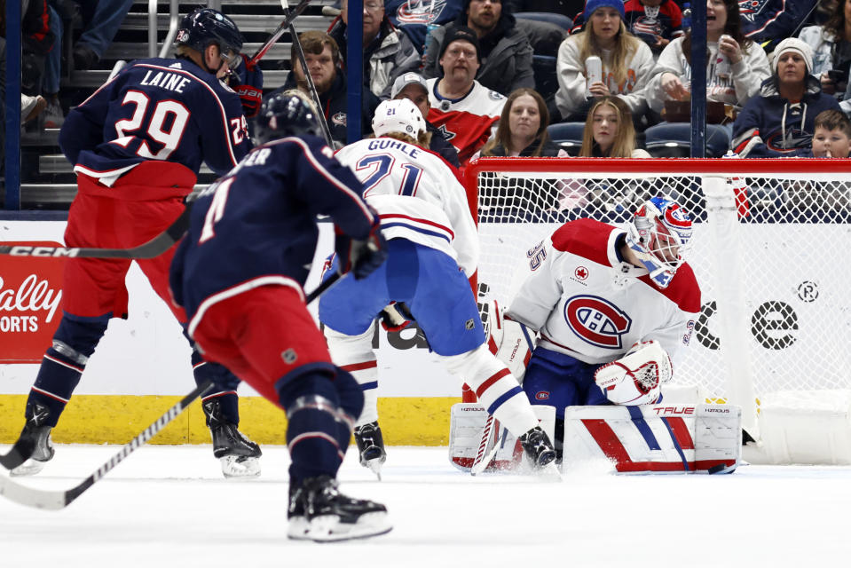 Montreal Canadiens goalie Sam Montembeault (35), stops a shot in front of teammate defenseman Kaiden Guhle (21), Columbus Blue Jackets forward Cole Sillinger (4) and forward Patrik Laine (29) during the first period of an NHL hockey game in Columbus, Ohio, Wednesday, Nov. 29, 2023. (AP Photo/Paul Vernon)