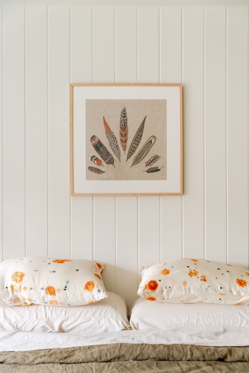 Feather art print above bed.