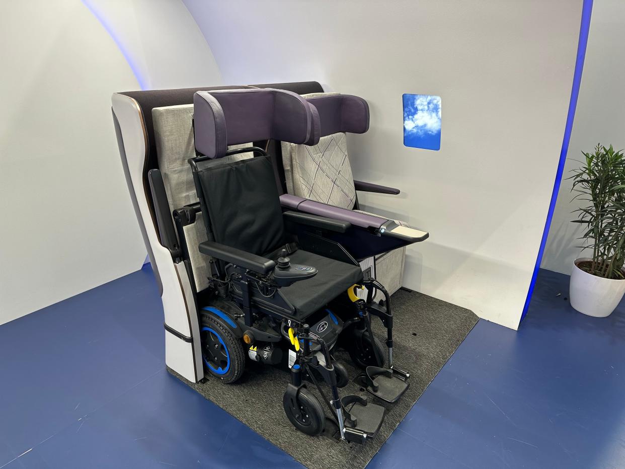 A wheelchair secured next to a standard domestic first class seat.
