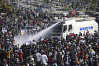 A police truck sprays water to a crowd of protesters in Naypyitaw, Myanmar, Monday, Feb. 8, 2021. In the month since Feb. 1 coup, the mass protests occurring each day are a sharp reminder of the long and bloody struggle for democracy in a country where the military ruled directly for more than five decades. (AP Photo)