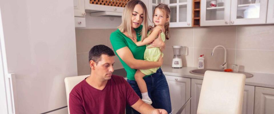 young smiling parent calculating bills at home