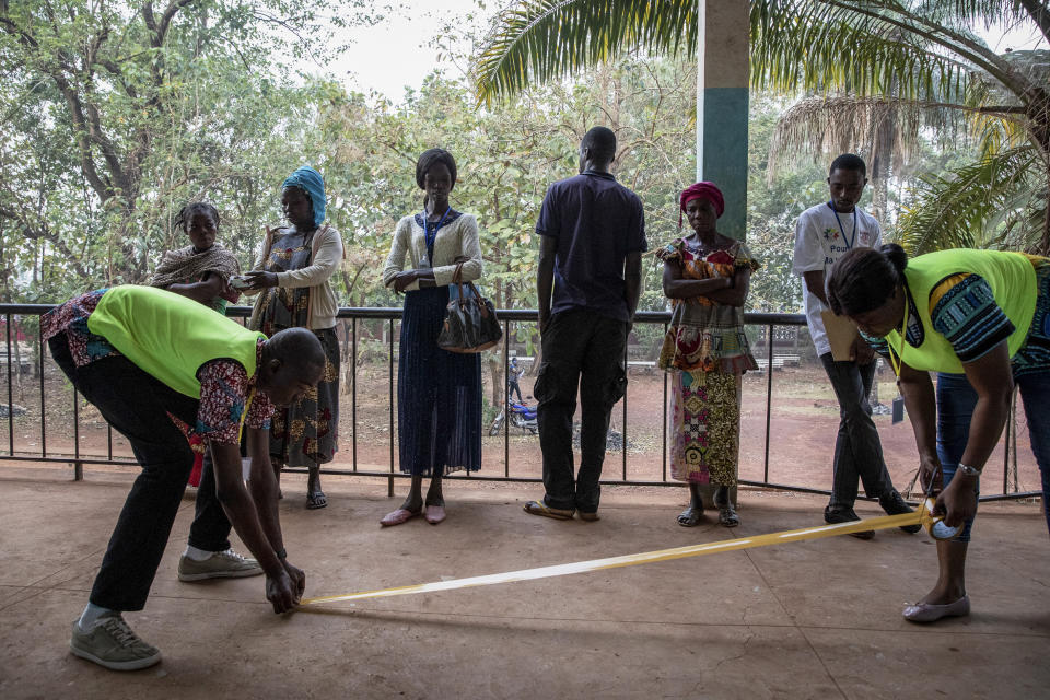 Electoral workers lay down tape as voters start to queue for presidential and legislative elections, at the Lycée Boganda polling station in the capital Bangui, Central African Republic Sunday, Dec. 27, 2020. President Faustin Archange Touadera and his party said the vote will go ahead after government forces clashed with rebels in recent days and some opposition candidates pulled out of the race amid growing insecurity. (AP Photo)