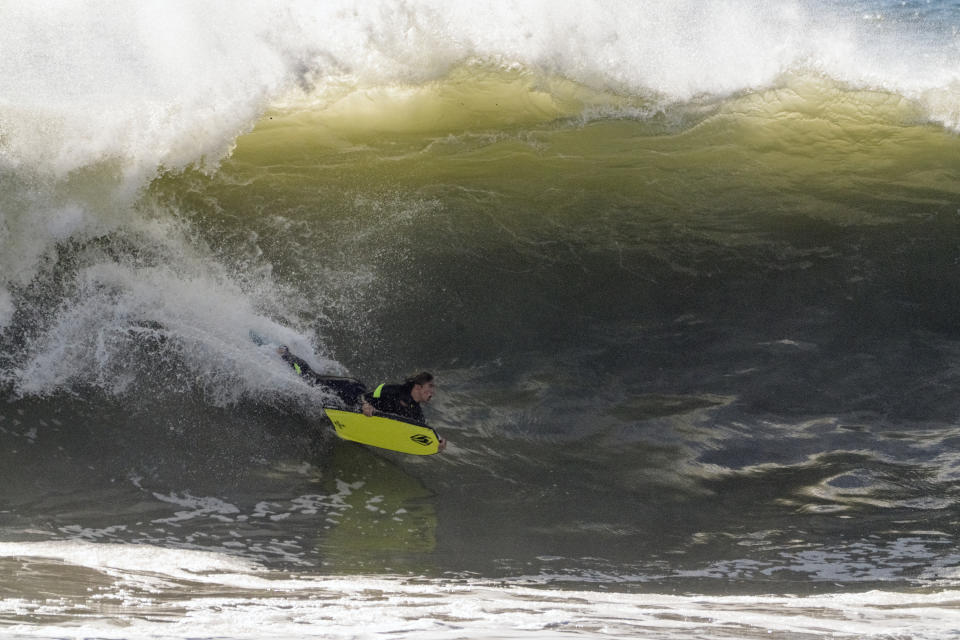 A surfer rides a wave in Seal Beach, Calif., Saturday, Dec. 30, 2023. The National Weather Service warns that another round of extremely dangerous surf conditions would return Saturday. (AP Photo/Damian Dovarganes)