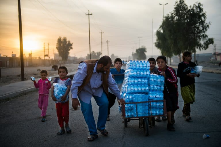 Iraqis push a cart loaded with bottles of water in the village of Gogjali, on the eastern outskirt of Mosul, on November 12, 2016