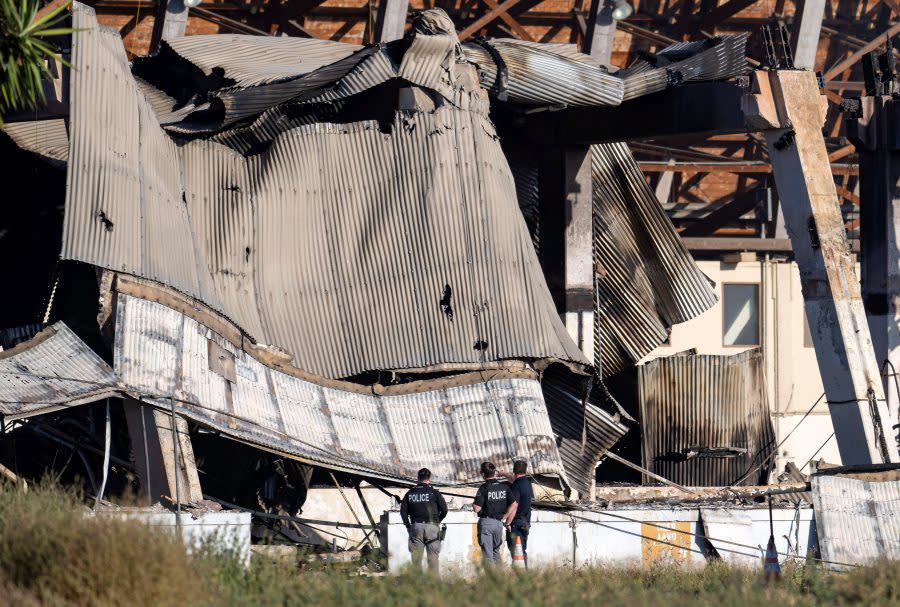 Officials investigate the rubble of the historic Tustin Marine Corps Air Station blimp hangar, Wednesday, Nov. 8, 2023, in Tustin, Calif., the day after a fire destroyed the WWII-era structure. (Mindy Schauer/The Orange County Register via AP)