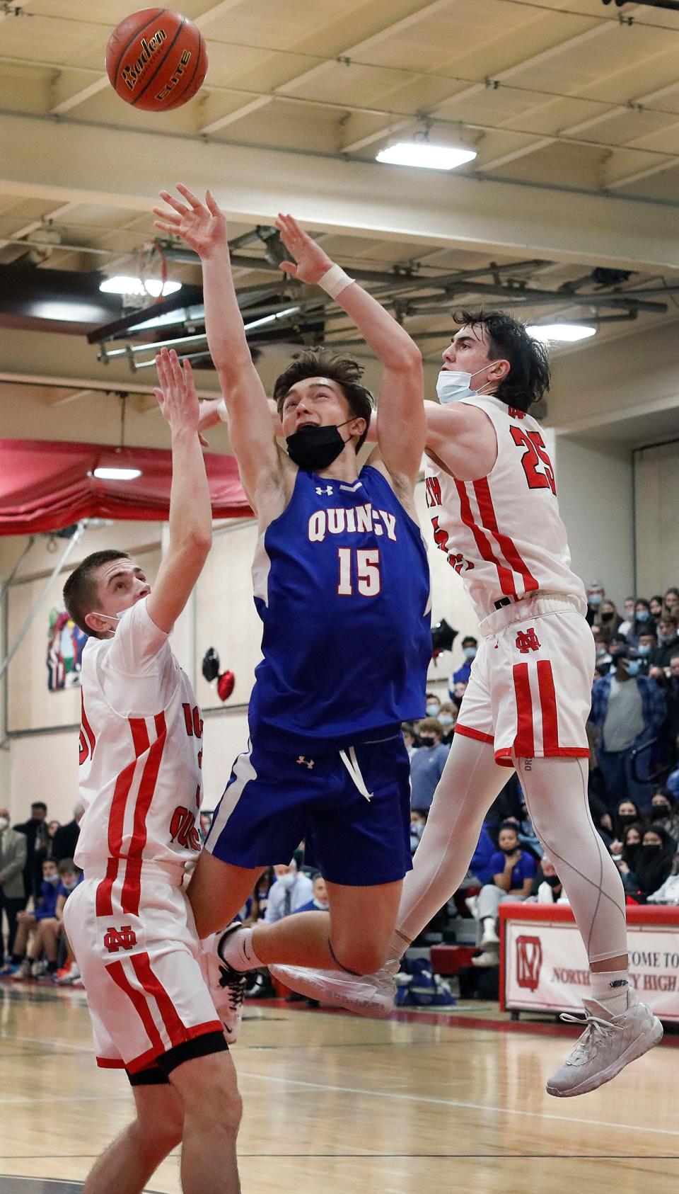 North Quincy's Daithi Quinn, right, tries to block the shot of Quincy's Caleb Parsons-Gomes. North Quincy hosted Quincy in a boys basketball game on Friday, Jan. 21, 2022.