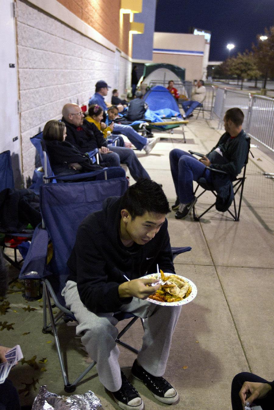 Khang Nguyen, of Arlington, Texas eats his Thanksgiving dinner while waiting in line at a Best Buy store in Grapevine, Texas on Thursday, Nov. 22, 2012. Despite a surge of resistance as the sales drew near, with scolding editorials and protests by retail employees and reminders of frantic tramplings past, Black Friday's grip on America may be stronger than ever. (AP Photo/Star-Telegram/Joyce Marshall)