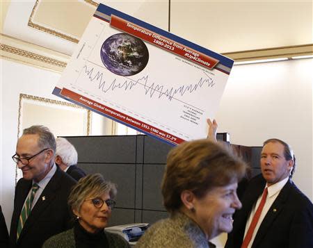 U.S. Senator Tom Udall (D-NM) (R) holds a poster as Senators from the Senate Climate Action Task Force meet before holding the Senate floor to urge action on climate change on Capitol Hill in Washington March 10, 2014. REUTERS/Yuri Gripas