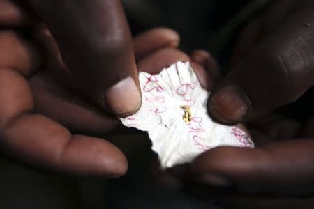 A Congolese mineral trader holds a piece of paper containing nuggets of gold in a mud hut at Numbi in eastern Congo in this July 24, 2010 file photo. REUTERS/Katrina Manson/Files