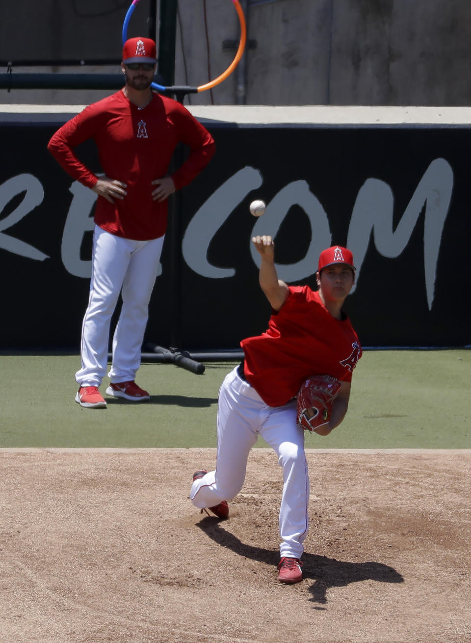 Los Angeles Angels' Shohei Ohtani, right, throws as pitching coach Doug White on in the bullpen before a baseball game against the Cincinnati Reds in Anaheim, Calif., Wednesday, June 26, 2019. Ohtani threw off a mound for the first time since Tommy John surgery Oct 1, 2018. (AP Photo/Chris Carlson)