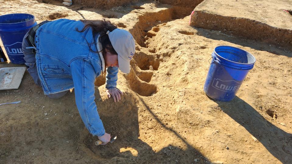 In this photo provided by John Crawmer, Jane C. Skinner excavates post holes at the bottom of a stockade trench, Thursday, Oct. 27, 2022, in York, Pa. Researchers say they have solved a decades-old riddle by finding remnants of the stockade and therefore the site of a prison camp in York, that housed British soldiers for nearly two years during the American Revolutionary War. (John Crawmer via AP)