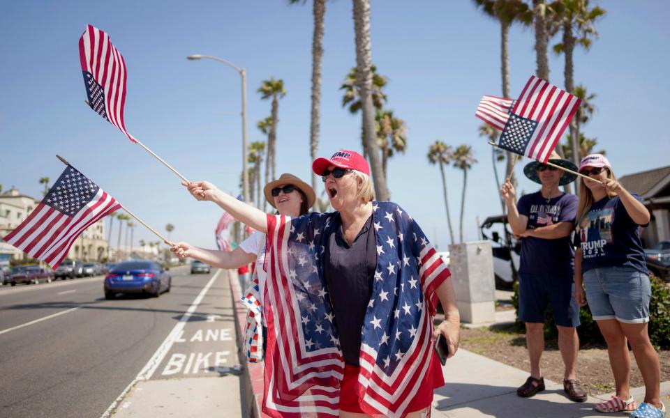 Attendees wave flags at vehicles at the rally in support of the presidential hopeful