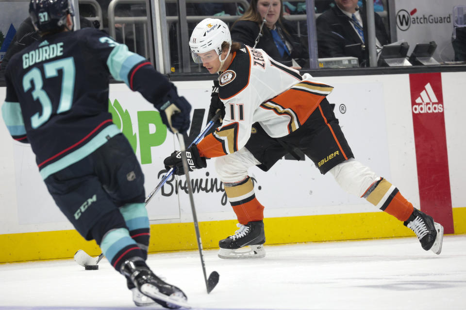 Anaheim Ducks center Trevor Zegras (11) moves the puck as Seattle Kraken center Yanni Gourde (37) defends during the second period of an NHL hockey game Tuesday, March 26, 2024, in Seattle. (AP Photo/Jason Redmond)