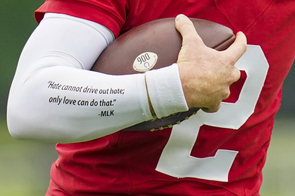 Indianapolis Colts quarterback Carson Wentz wears a quote from Martin Luther King on his sleeve as runs a drill during practice at the NFL team's football training camp in Westfield, Ind., Wednesday, July 28, 2021. (AP Photo/Michael Conroy)