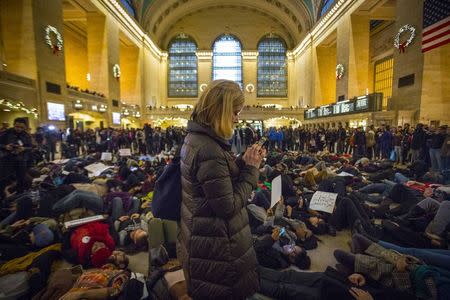 A woman photographs protesters performing a "Die-In" at Grand Central Station during a march for chokehold death victim Eric Garner in New York December 6, 2014. REUTERS/Andrew Kelly