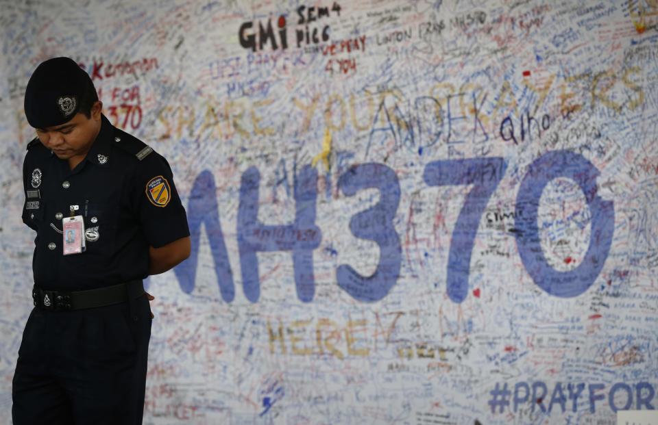 Malaysia airport police officer stands in front of messages board for the passengers aboard a missing Malaysia Airlines plane at Kuala Lumpur International Airport in Sepang, Malaysia, Wednesday, March 19, 2014. New radar data from Thailand gave Malaysian investigators more potential clues Wednesday for how to retrace the course of the missing Malaysian airliner, while a massive multinational search unfolded in an area the size of Australia. (AP Photo/Vincent Thian)