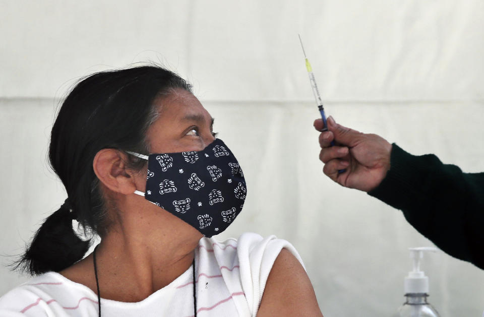 FILE - In this Feb. 15, 2021 file photo, a woman eyes a syringe as she prepares to be inoculated with a dose of the AstraZeneca vaccine against COVID-19 in the Magdalena Contreras area of Mexico City, during a vaccination campaign for the elderly. As Mexico approaches 200,000 in officially test-confirmed deaths from COVID-19, the real death toll is probably higher due to the country’s extremely low rate of testing. (AP Photo/Marco Ugarte, File)