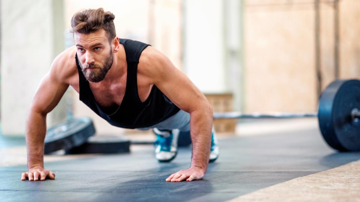  Man performing push-ups in gym studio during workout. 