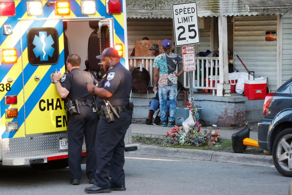 A Savannah Police officer talks with a gunshot victim in the back of an ambulance on East Bolton Street near a roadside memorial for Maurice Mincey, who was killed by a police officer during a traffic stop in July.