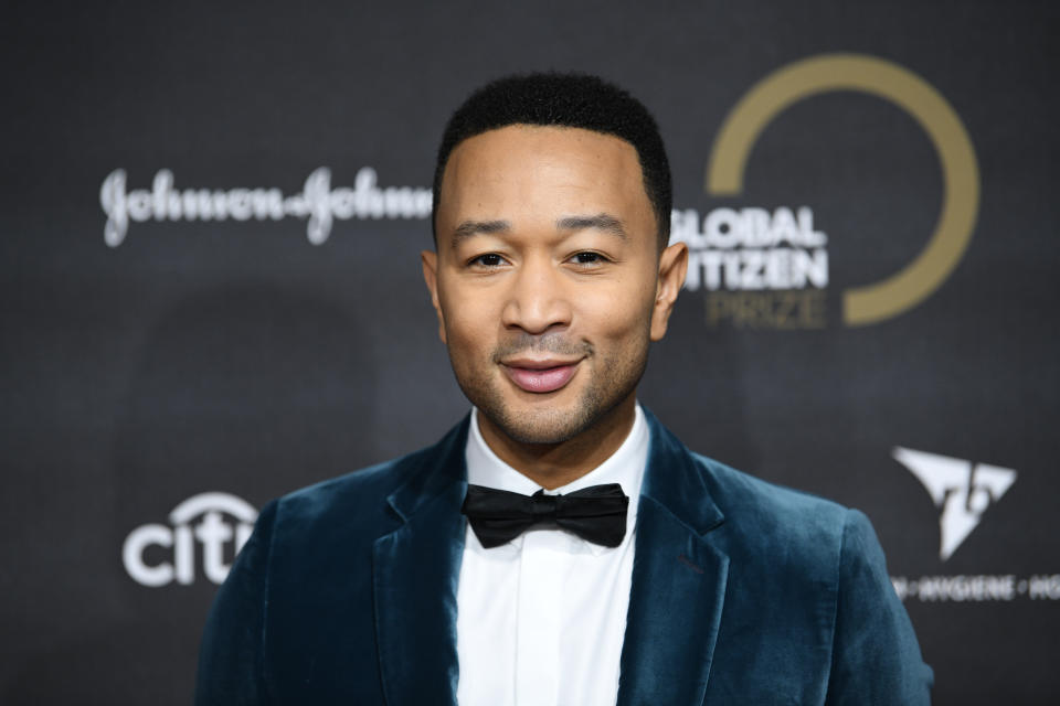 Close-up of John smiling in a suit and bow tie at a media event