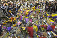 Fans gather in front of several memorials set up at LA Live, near Staples Center where the Los Angeles Lakers play, to memorialize Kobe Bryant Tuesday, Jan. 28, 2020, in Los Angeles following a helicopter crash that killed the former NBA basketball player, his 13-year-old daughter, Gianna, and seven others. (AP Photo/Mark J. Terrill)