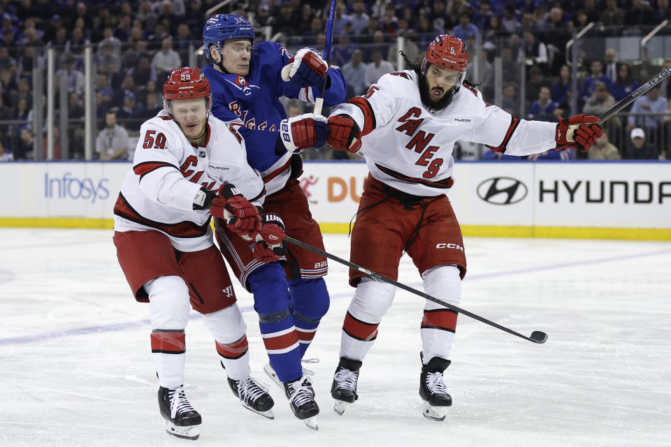 Carolina Hurricanes defenseman Jalen Chatfield (5) checks New York Rangers right wing Kaapo Kakko, center, into Hurricanes center Jake Guentzel (59) in the first period during Game 5 of an NHL hockey Stanley Cup second-round playoff series Monday, May 13, 2024, in New York. (AP Photo/Adam Hunger)