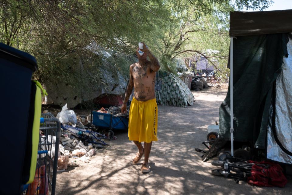 Daniel (no last name) drinks out of a frozen water bottle given to him by Carry Forwardon  June 30, 2023, in a homeless encampment on the Tempe/Phoenix border.