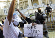 Women wearing face shields against the spread of the new coronavirus, protest against crimes committed by the police against black people in the favelas, outside the Rio de Janeiro's state government, Brazil, Sunday, May 31, 2020. The protest, called "Black lives matter," was interrupted when police used tear gas to disperse people. "I can't breathe", said some of the demonstrators, alluding to the George Floyd's death. (AP Photo/Silvia Izquierdo)