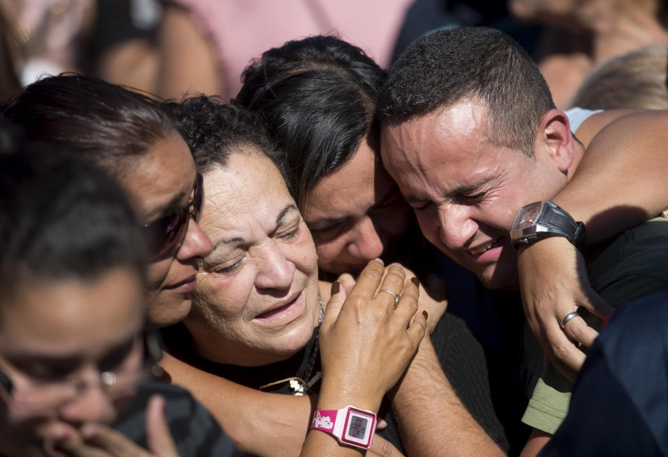 Relatives of Arlinda Bezerra, a resident of the Alemao slum killed during a weekend shootout, mourn during her burial at the Inhauma cemetery in Rio de Janeiro, Brazil, Tuesday, April 29, 2014. Bezerra died on Sunday when a stray bullet hit her in the stomach during a shootout between police and alleged drug traffickers. Three cars were torched in retaliation adding to the latest wave of violence in Rio's slums. Tensions have been rising in recent months amid an ambitious security push that sees officers enter slums long held by drug gangs then create permanent police posts. (AP Photo/Silvia Izquierdo)