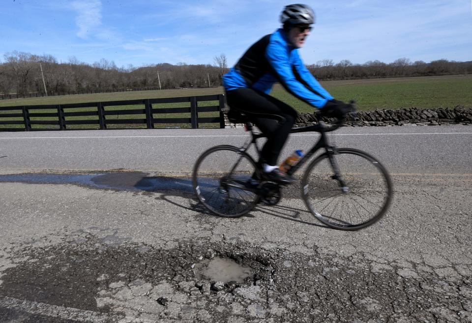 A biker avoids a pothole on Moran Road in Franklin on Monday, Feb. 25, 2019. 